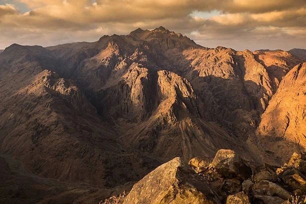 Mount Sinai summit at sunrise with golden hues over the desert.