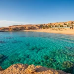 Panoramic view of a luxury resort and pristine turquoise waters of the Red Sea in Sharm El Sheikh, Egypt, hinting at exclusive marine adventures.